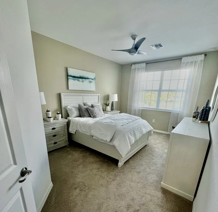 Guest bedroom with whitewashed furnishings, neutral bedding, and sheer curtains