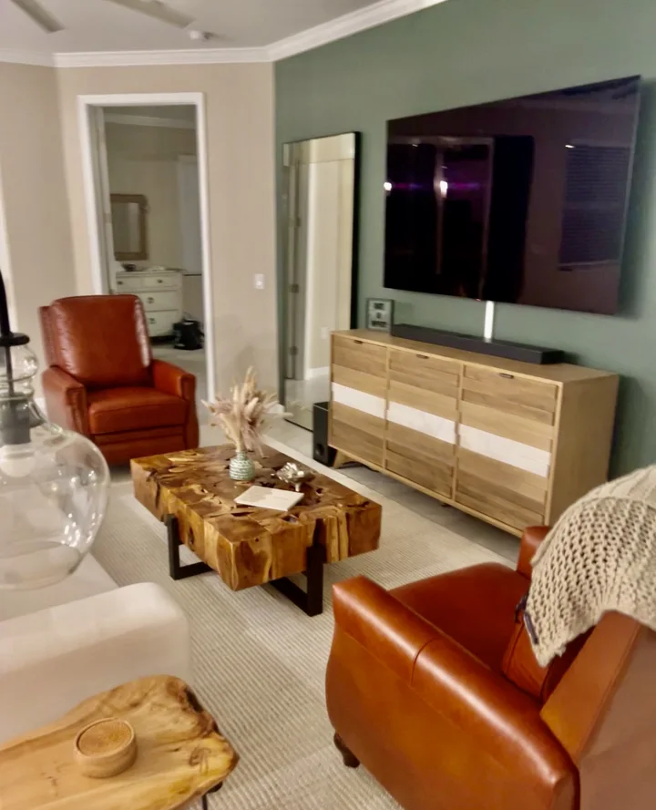 Living area with cognac leather chairs, a sculptural wood table, and a media console