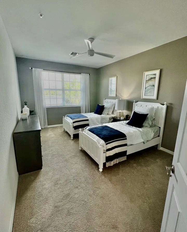 Twin bedroom with white beds, navy accents, and coordinated artwork